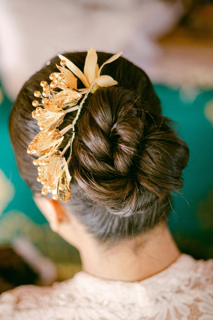 Close-up of an elegant bridal updo hairstyle adorned with a golden floral hairpiece.